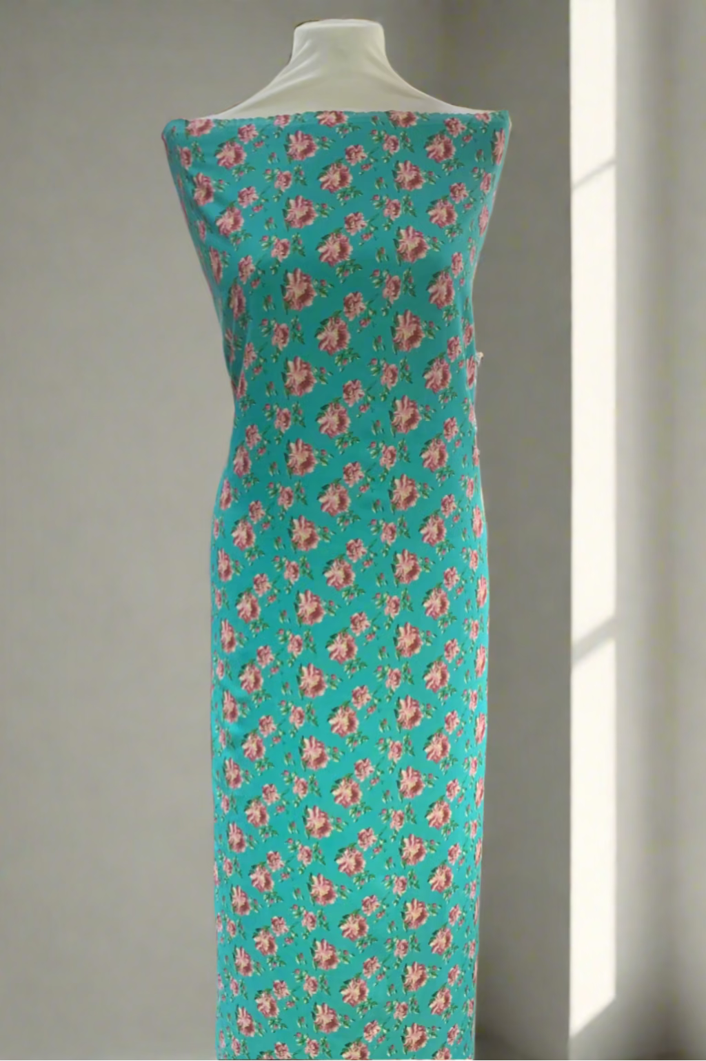 Teal fabric with pink floral pattern on a mannequin in a store setting