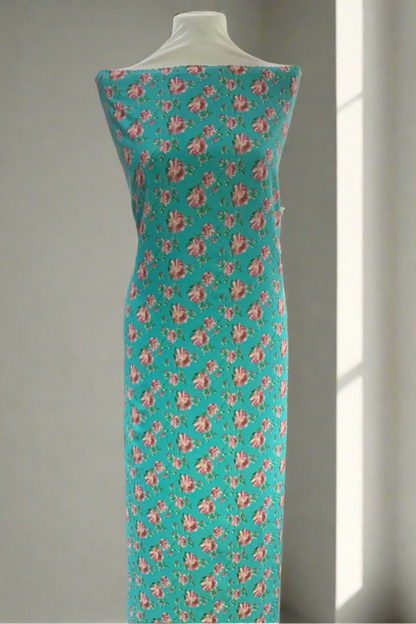 Teal fabric with pink floral pattern on a mannequin in a store setting