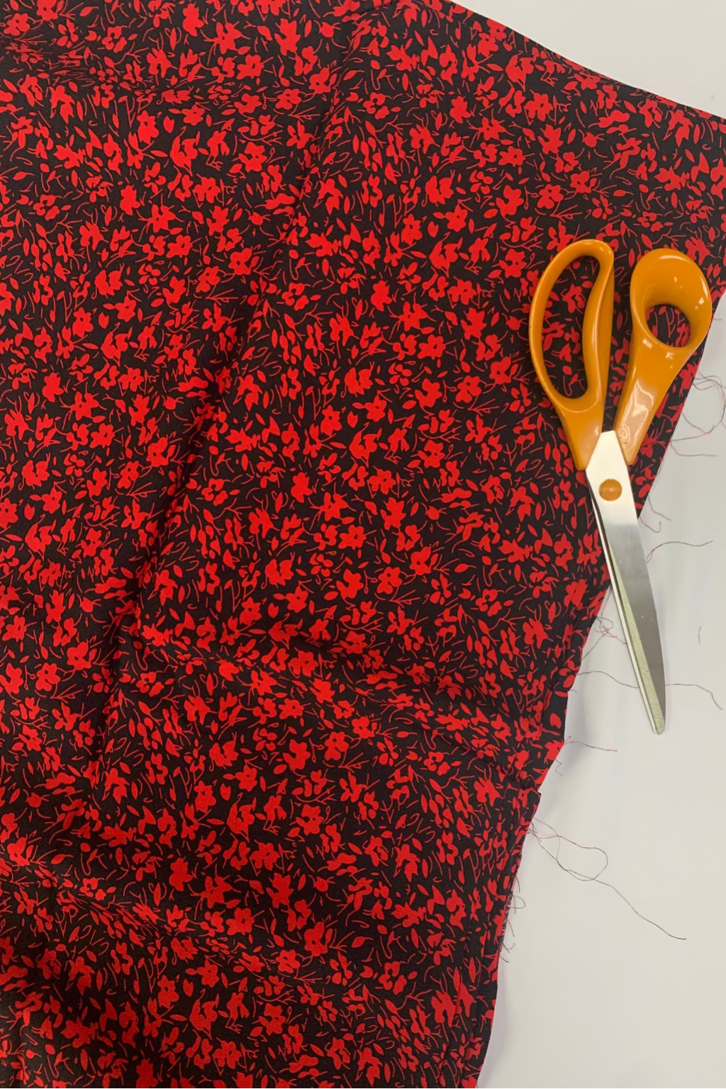 Red and black floral fabric with a pair of scissors on a white background