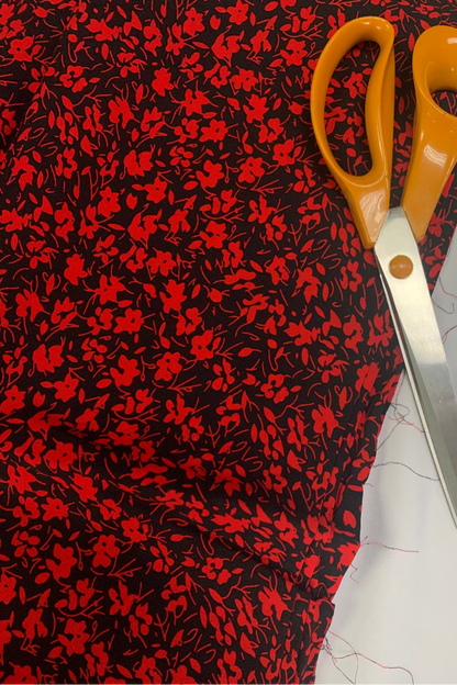 Scissors on a piece of red and black floral fabric