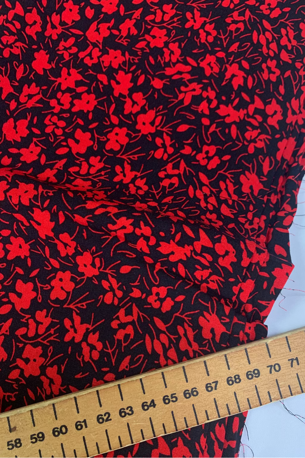 Red floral pattern on black fabric with a ruler for scale
