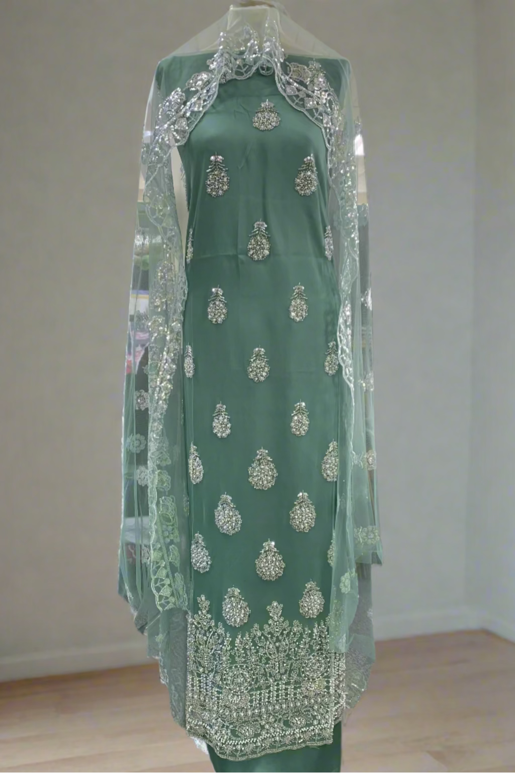 Green fancy party dress on a mannequin in a store setting