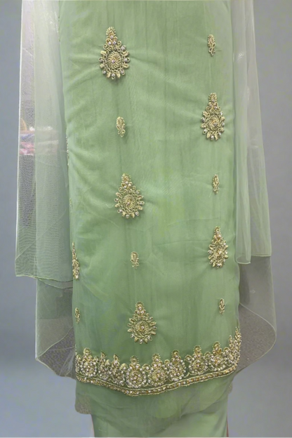Light green traditional outfit with gold embroidery in a store setting