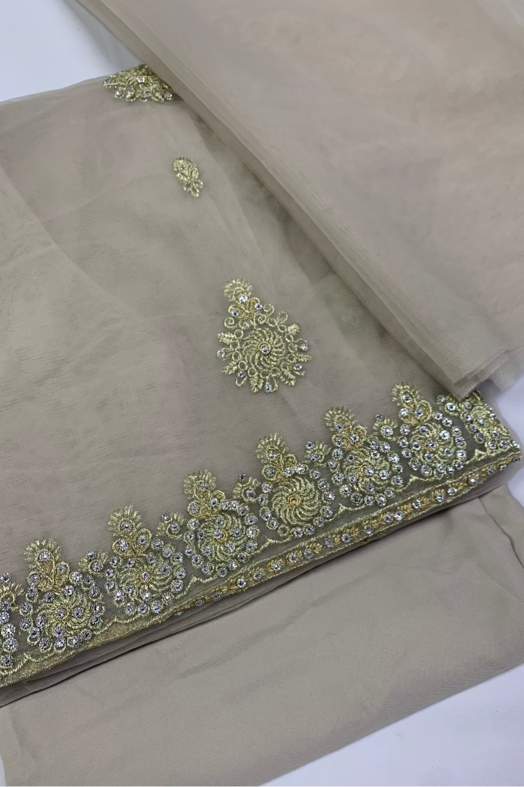 Beige fabric with intricate gold embroidery on a white background