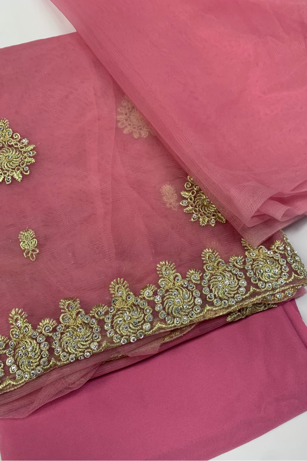 Pink fabric with gold embroidery on a white background