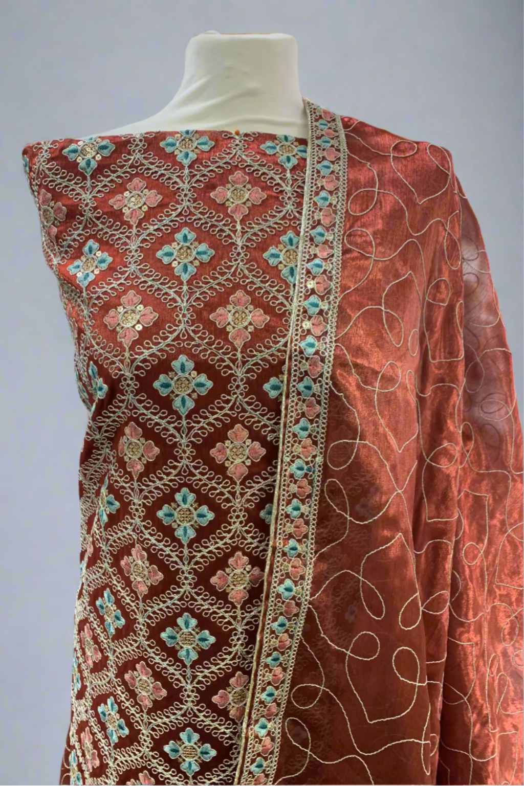 Orange fabric with intricate embroidery on a mannequin in a store setting