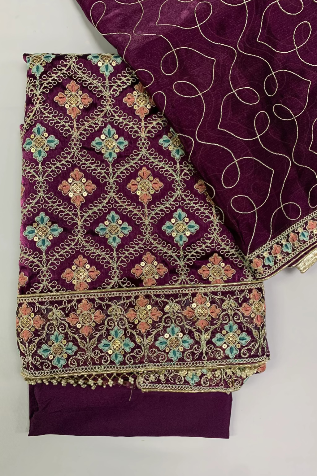 Purple fabric with intricate gold and multicolor embroidery on a white background