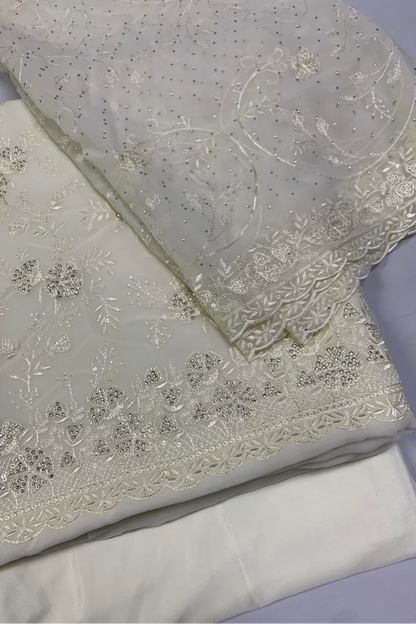 White fabric with intricate silver embroidery on a light purple background