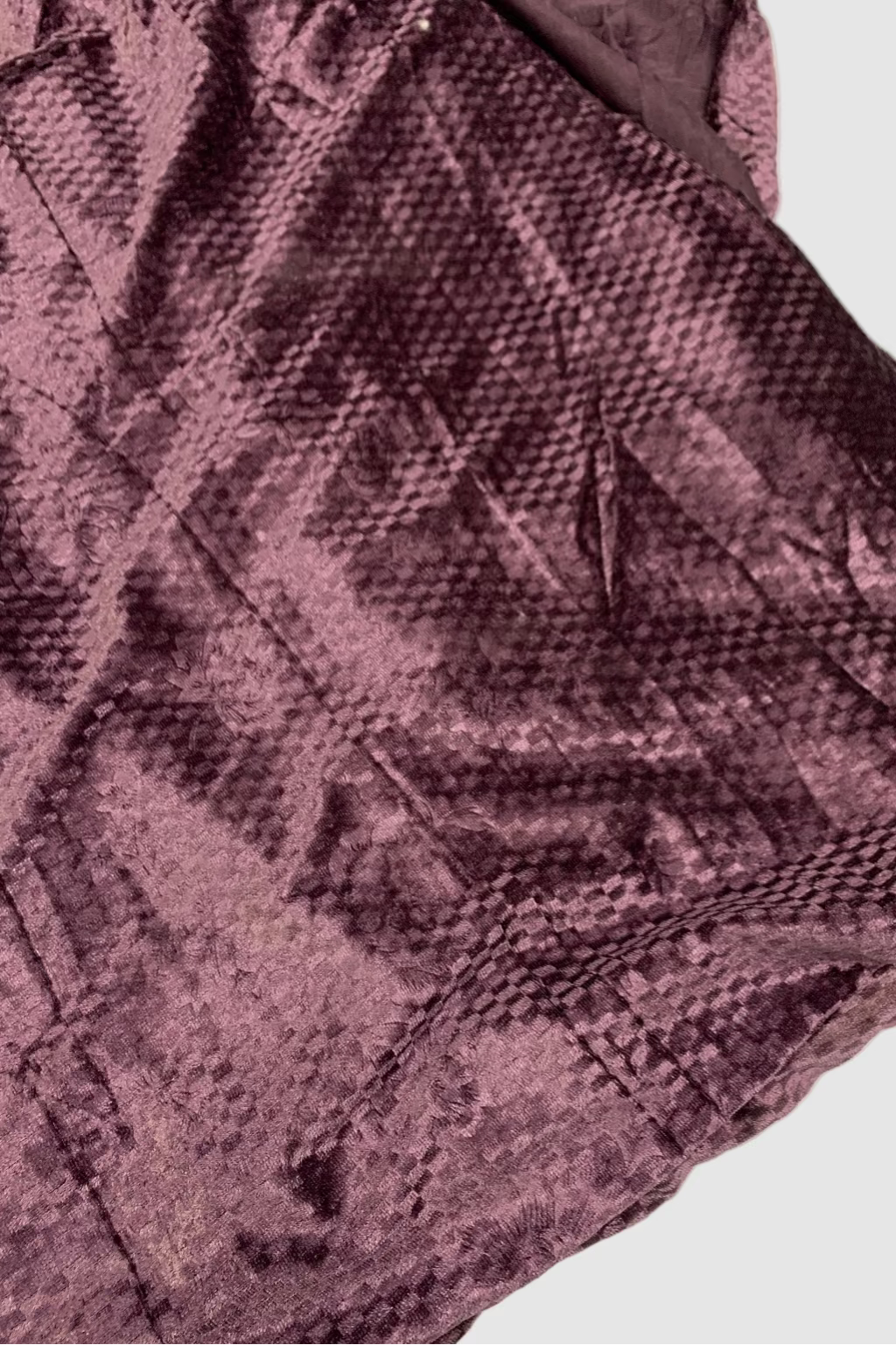 Close-up of a textured purple fabric with a diamond pattern on a white background