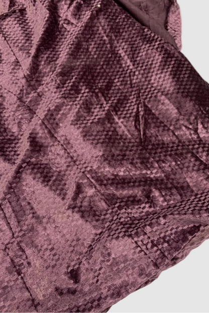 Close-up of a textured purple fabric with a diamond pattern on a white background