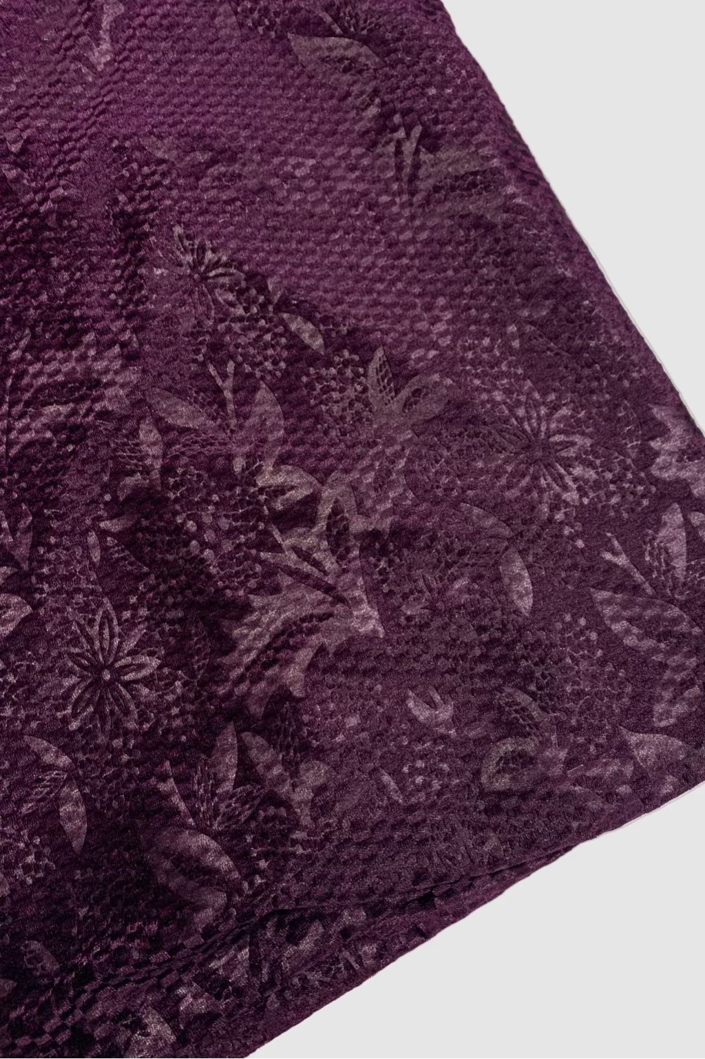 Close-up of a purple fabric with floral pattern on a white background