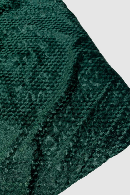 Close-up of a textured green fabric with a subtle pattern on a white background