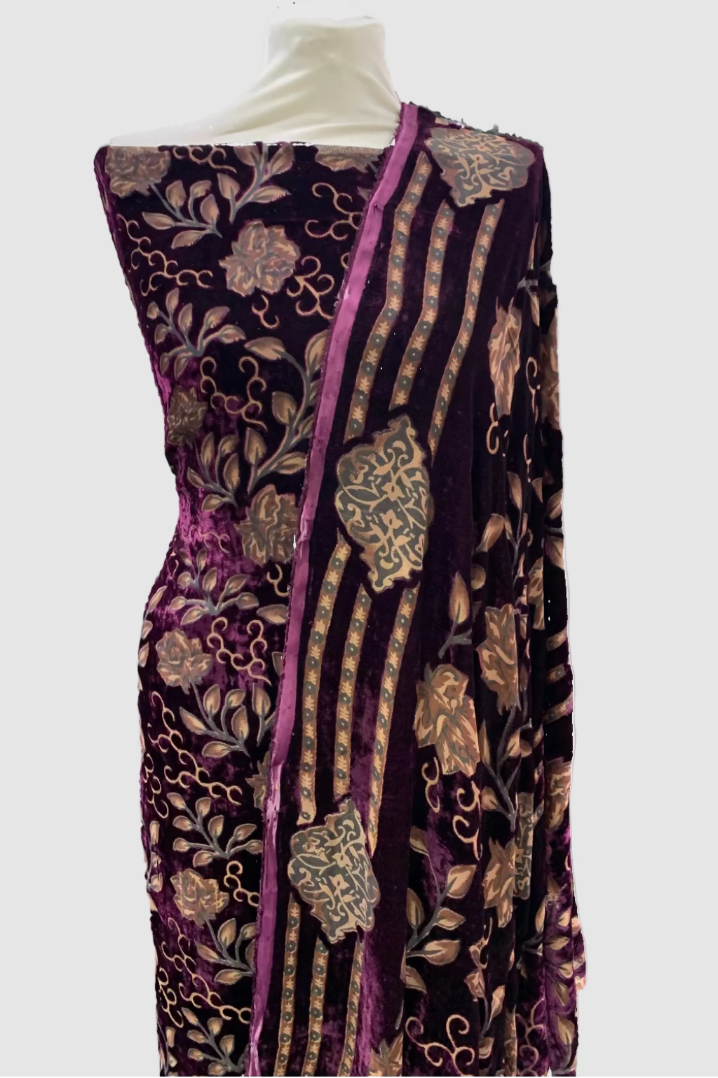 Decorative fabric with intricate patterns on a mannequin in a store setting.