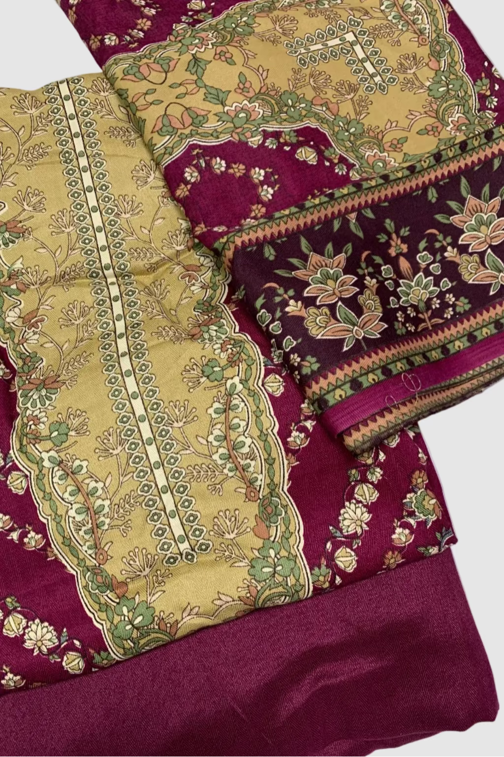 Traditional fabric with intricate gold and green patterns on a maroon background
