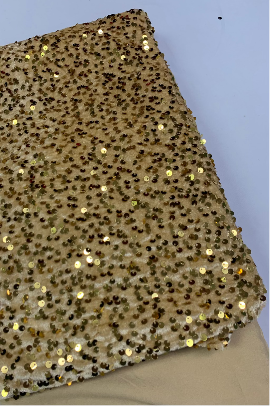 Gold fabric with gold sequins on a light grey background