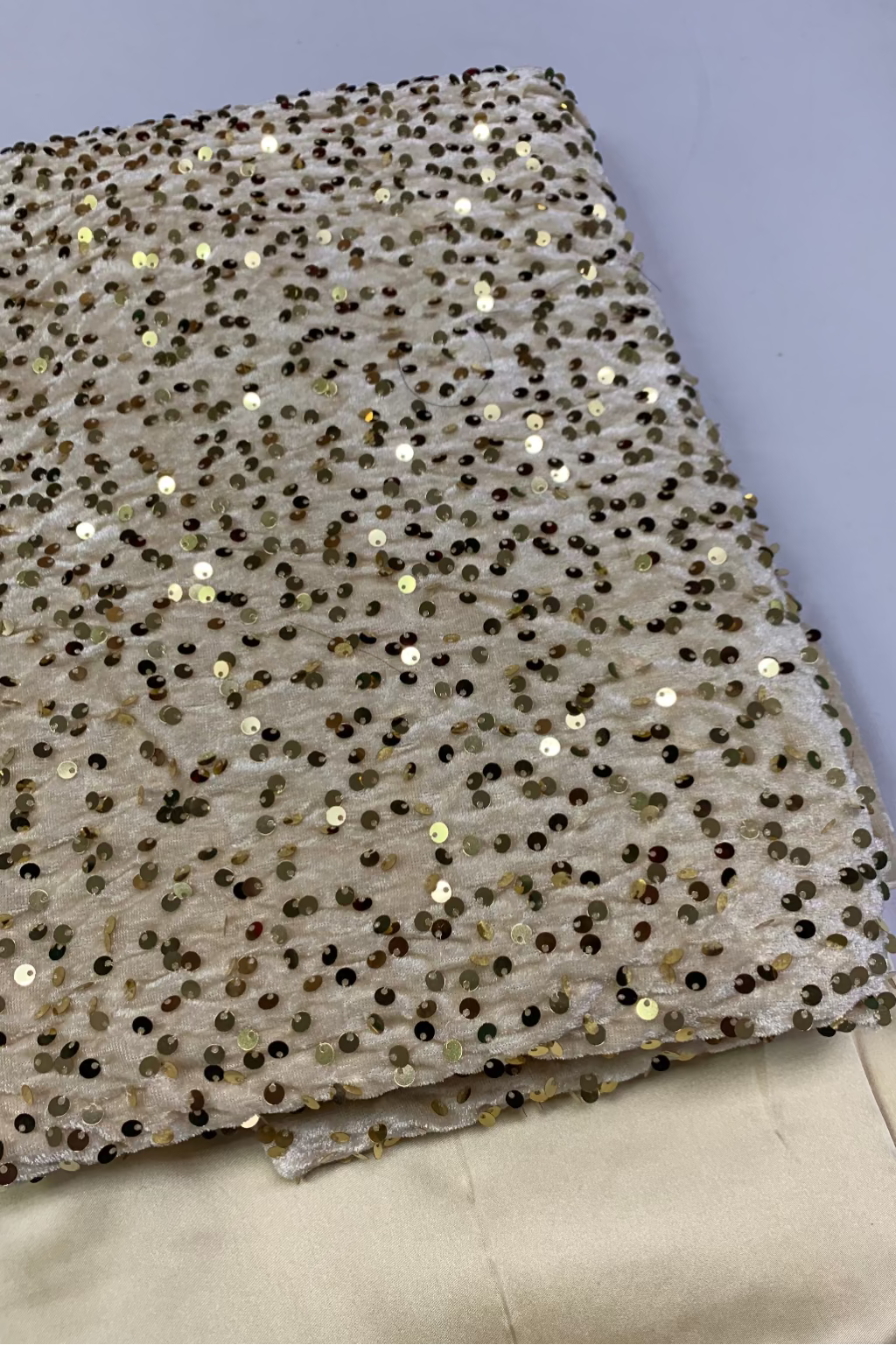 Beige fabric with gold sequins on a light gray background
