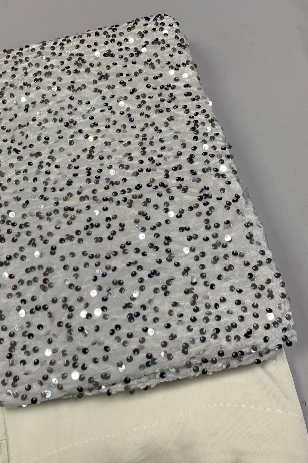 White sequin velvet fabric on a gray background