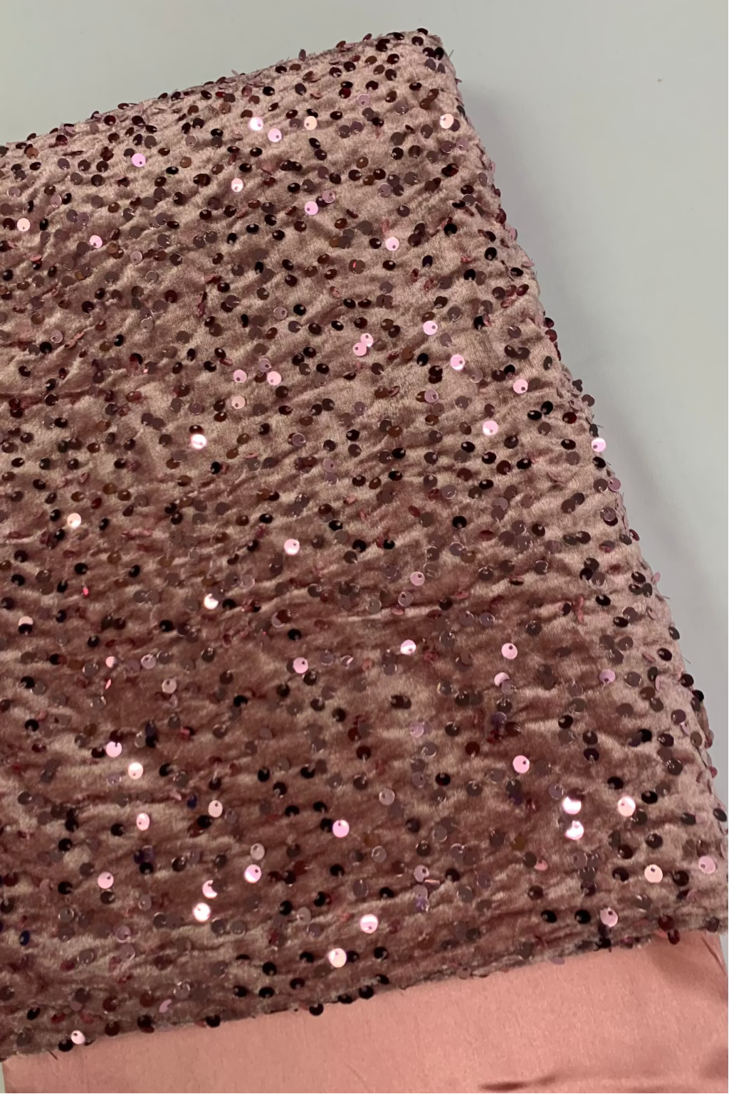 Peach velvet fabric with sequins on a light grey background