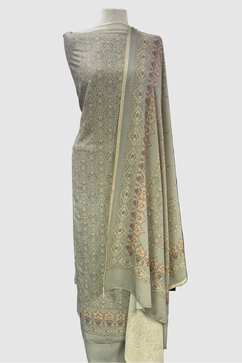 Grey unstitched suit with intricate patterns on a mannequin in a fabric store.