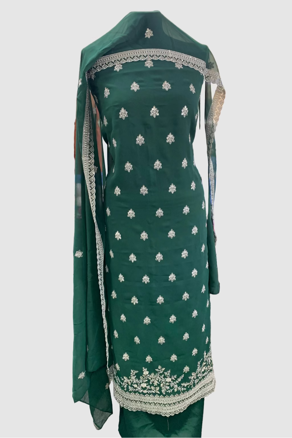 Green embroidered traditional outfit in a store setting