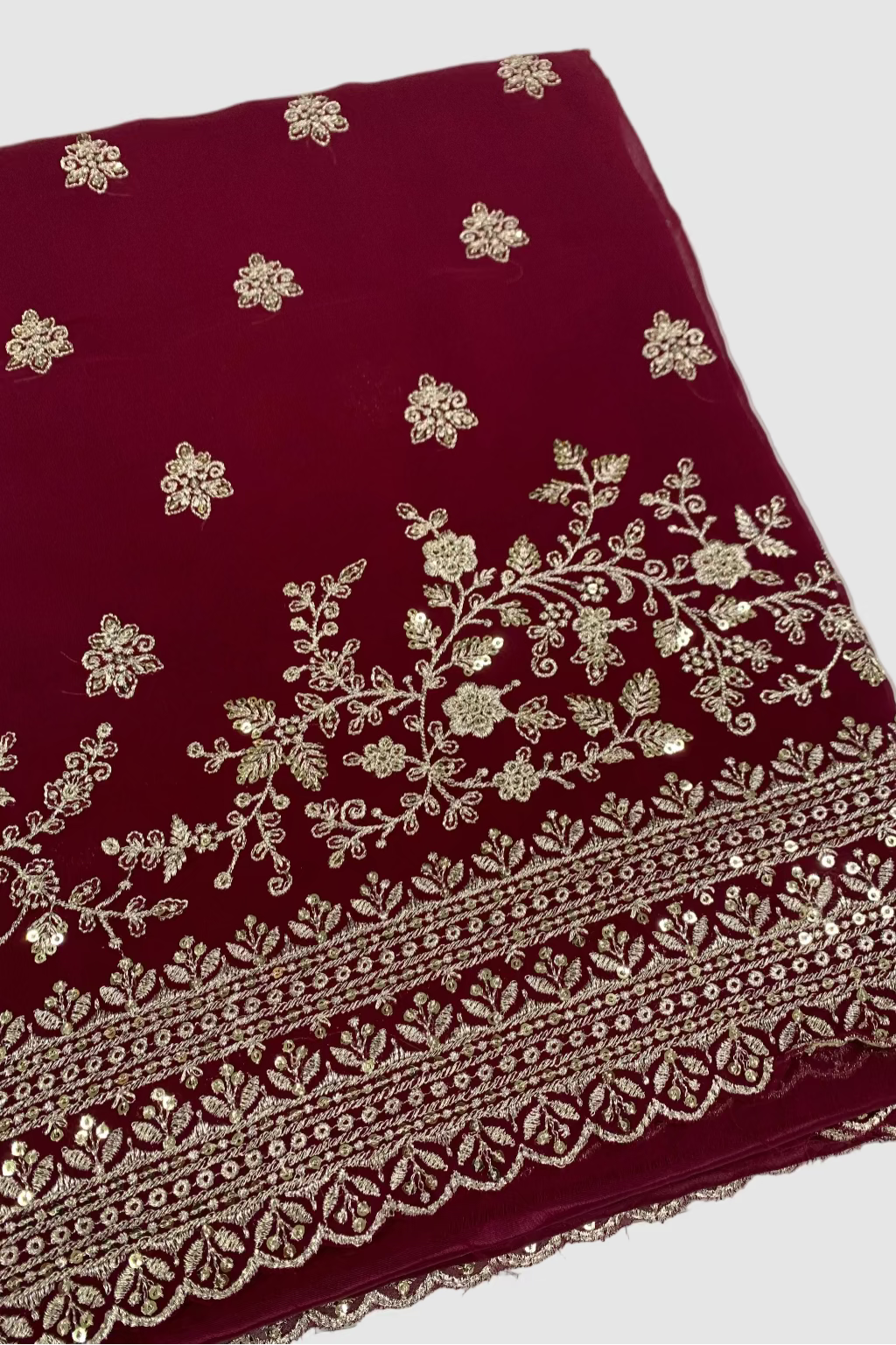 Maroon fabric with silver floral embroidery on a white background