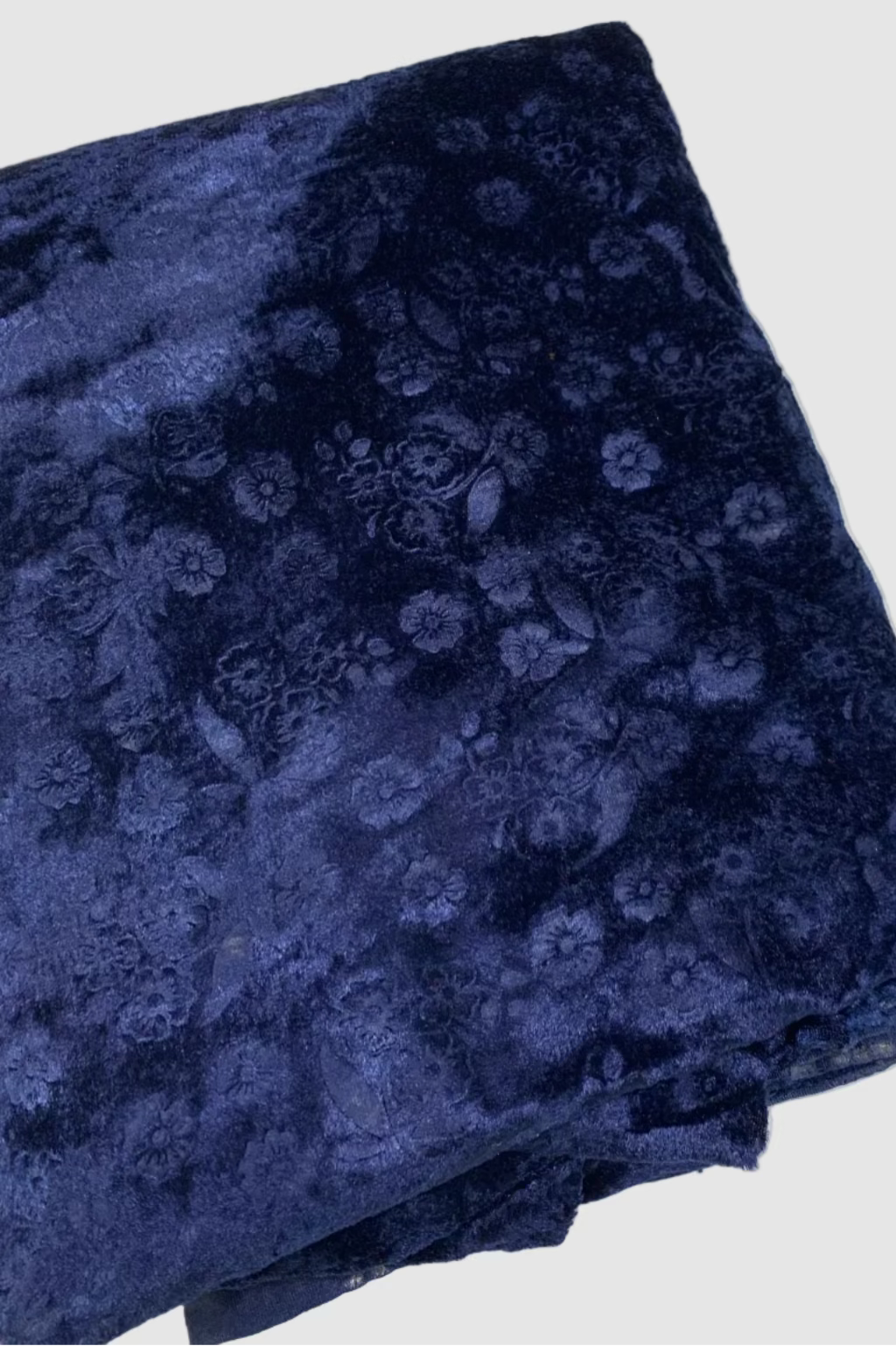 Folded navy blue fabric with floral pattern on a white background