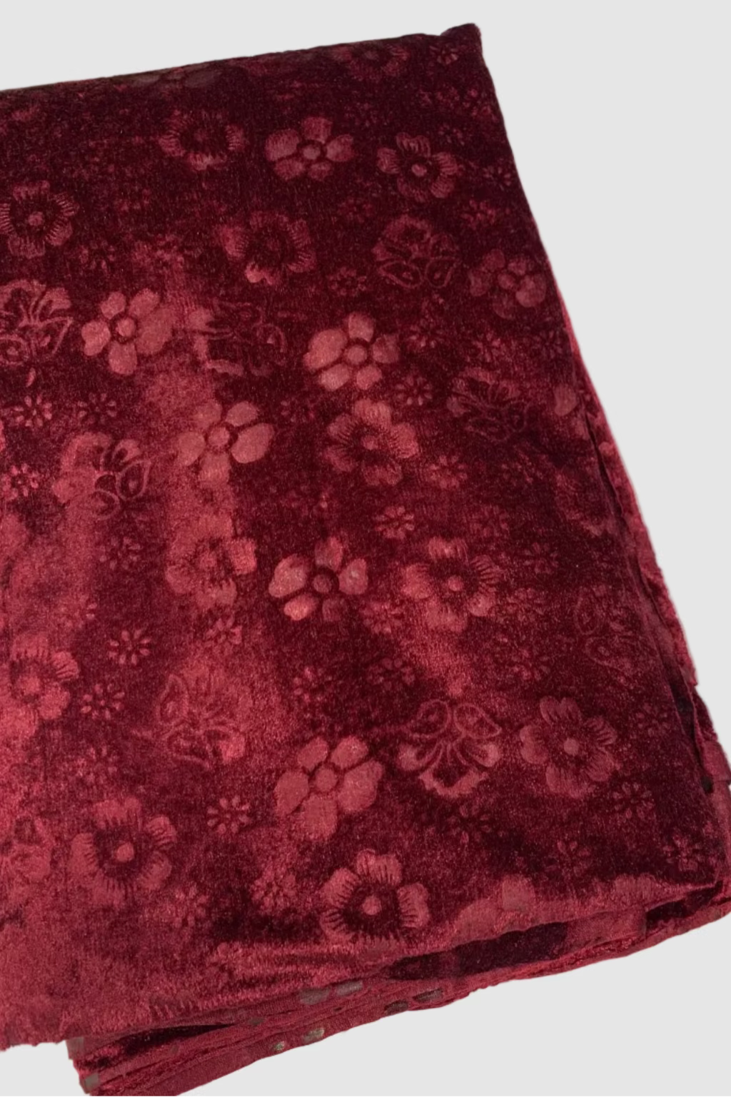 Folded maroon fabric with floral pattern on a white background