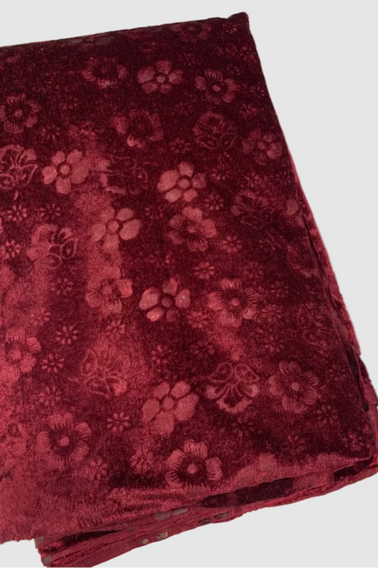 Folded maroon fabric with floral pattern on a white background