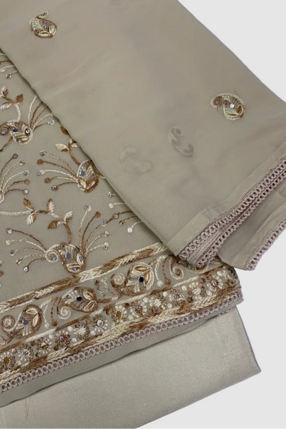 Beige fabric with intricate gold embroidery on a white background