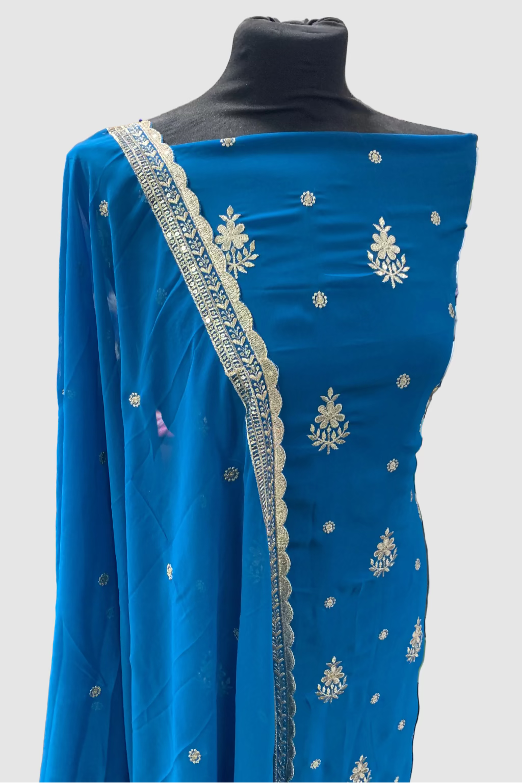 Blue embroidered dress fabric on a mannequin in a store setting