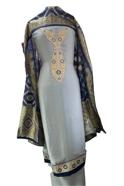 Traditional outfit with gold and blue embroidery on a mannequin in a store setting.