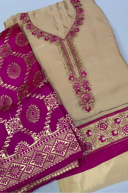 Beige fabric with intricate magenta and gold embroidery on a white background