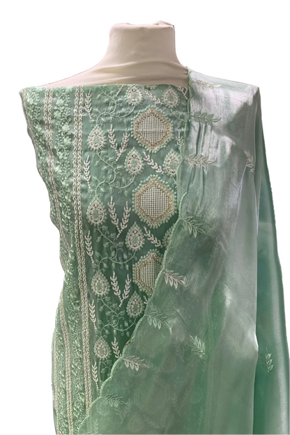 Green embroidered fabric on a mannequin in a store setting