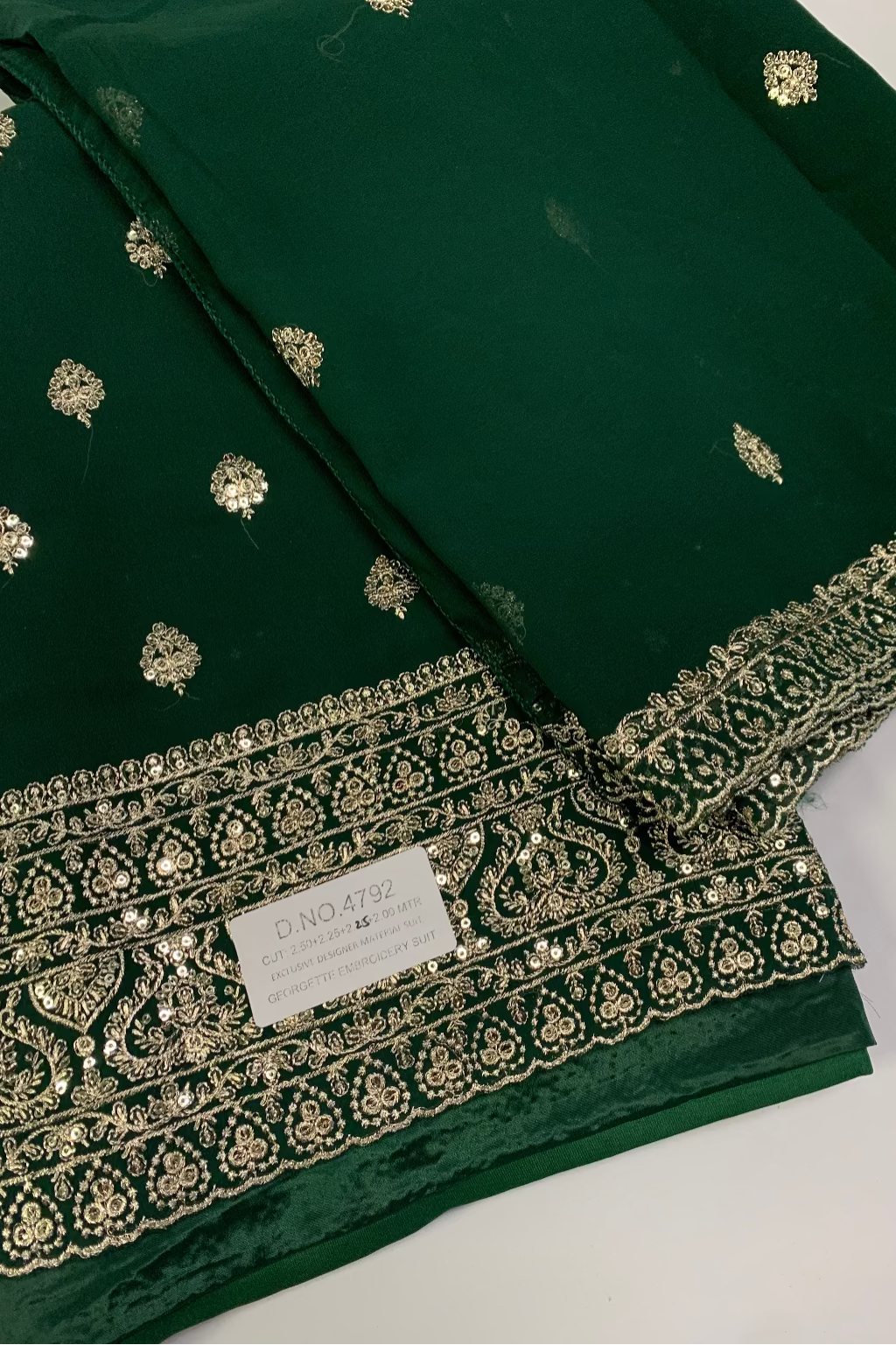 Green fabric with gold embroidery and a label on a white background