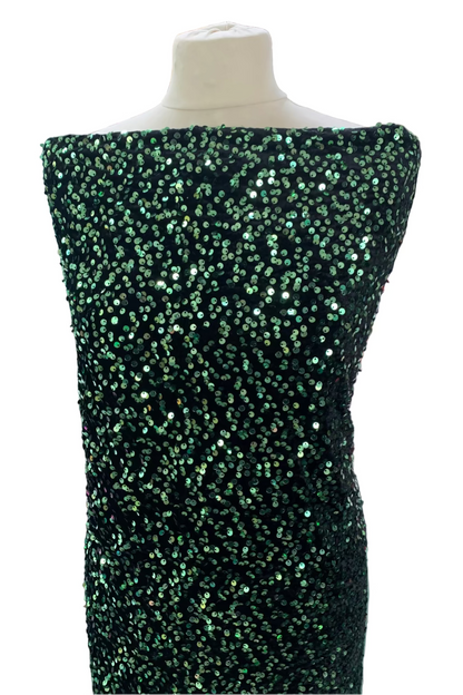Mannequin wearing a green sequined dress in a fabric store.