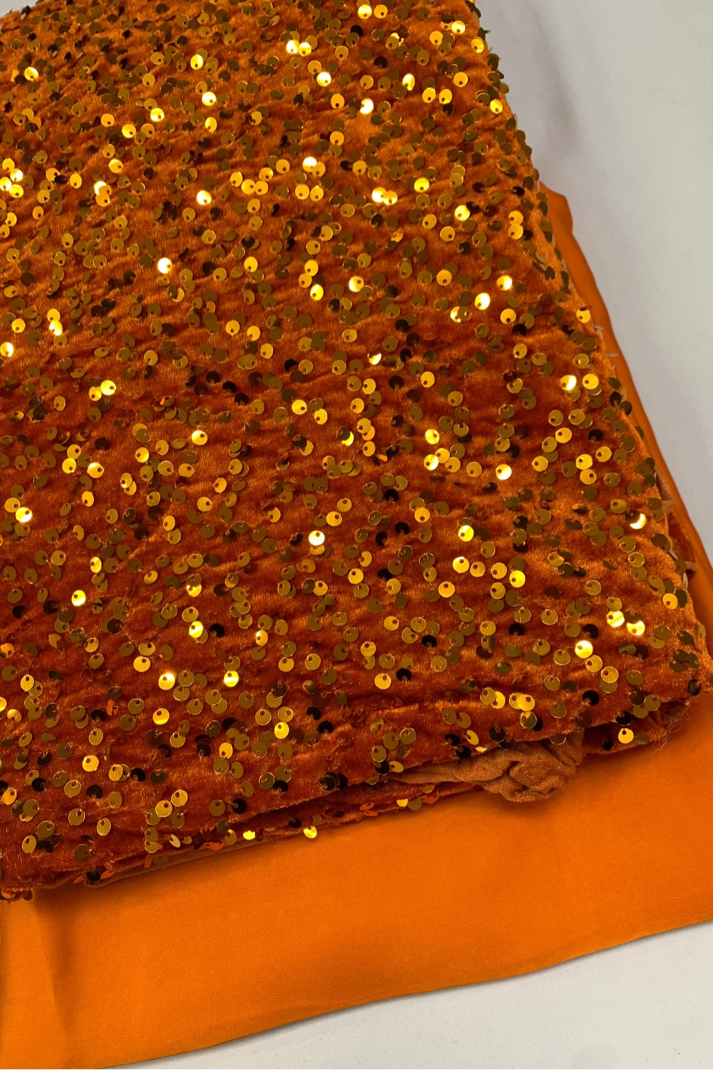 orange fabric with gold sequins on a white background