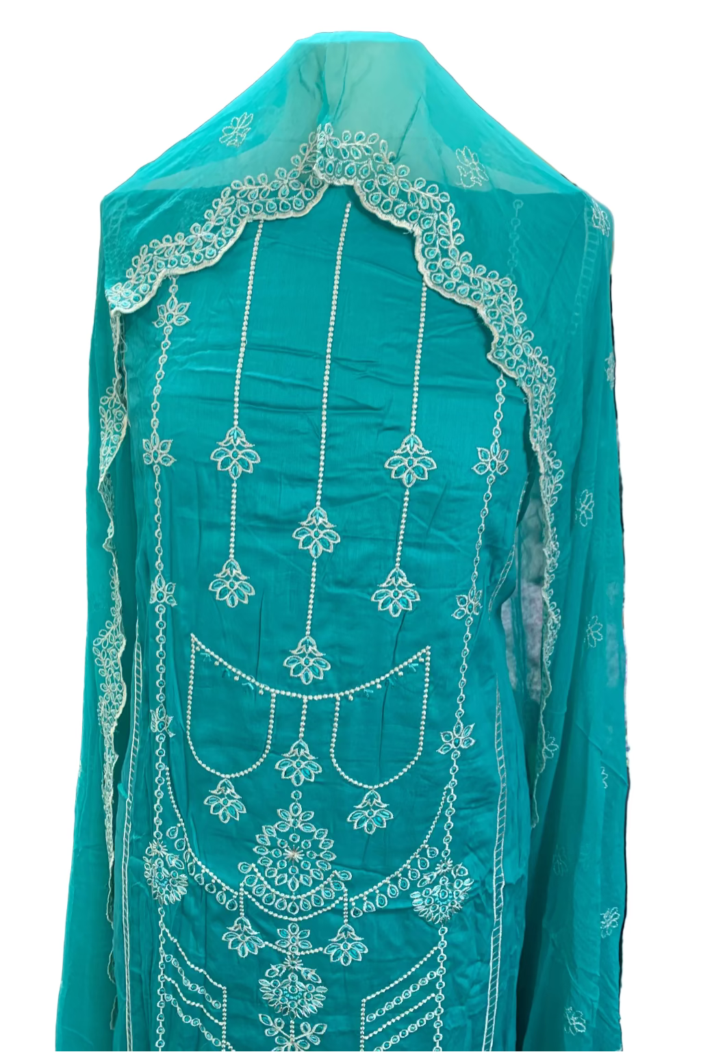 Turquoise embroidered fabric with intricate white patterns in a store setting