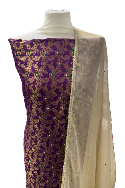 Mannequin wearing a purple and gold embroidered fabric with a beige border in a store setting.