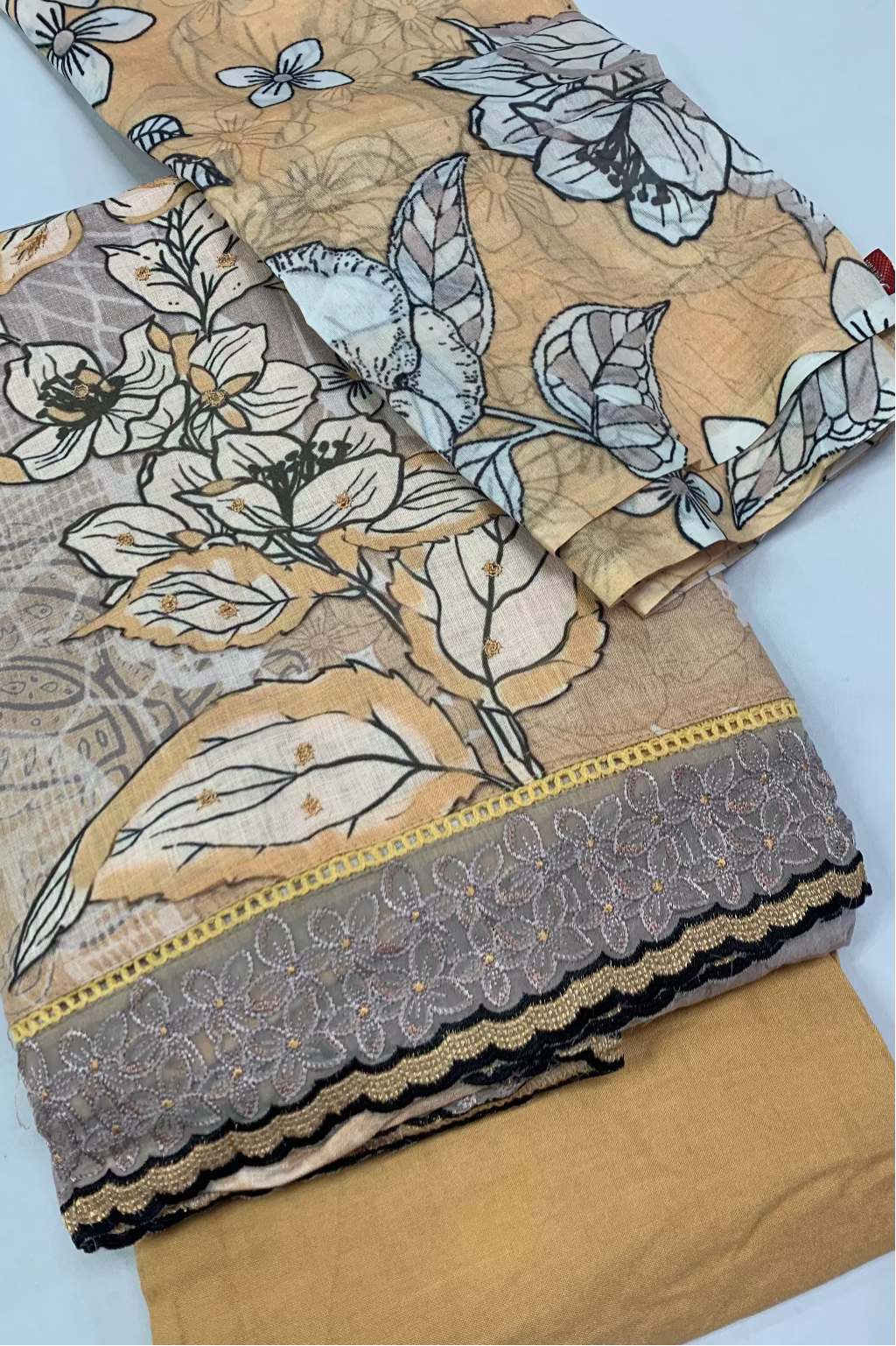 Stack of fabric with floral and leaf patterns on a light blue background