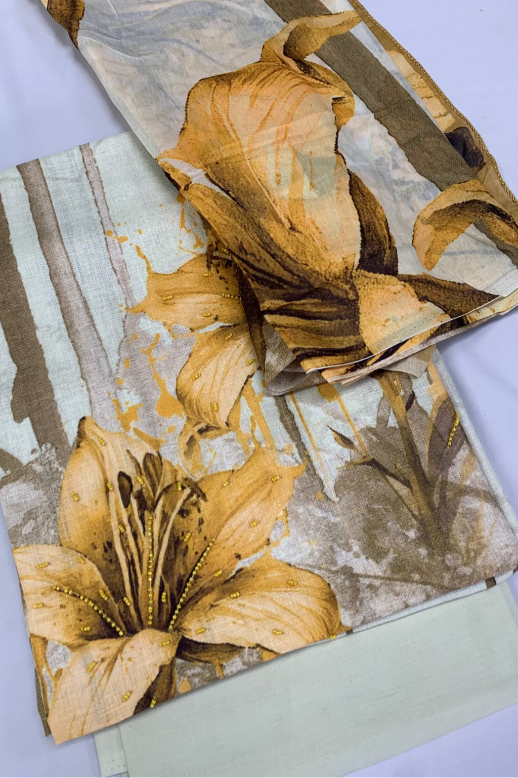 Floral patterned fabric with gold and brown tones on a white background