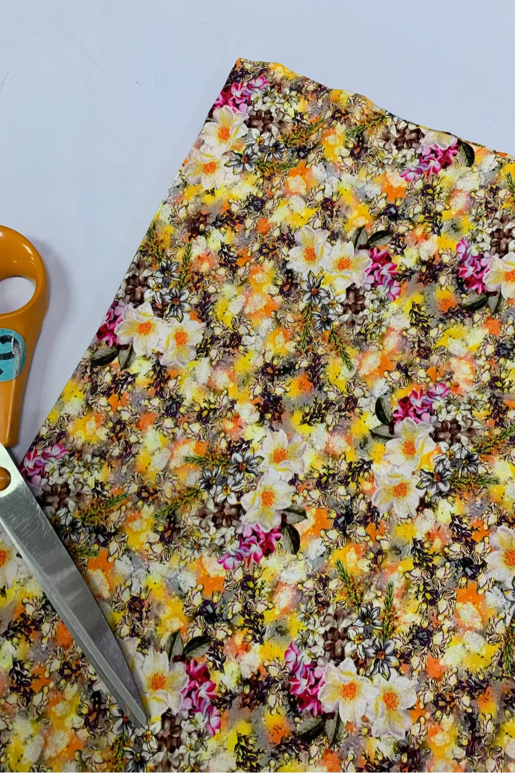 Colourful floral fabric with a pair of scissors on a white background