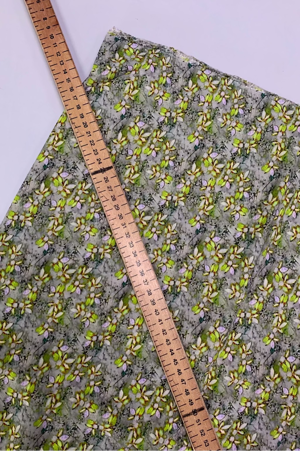 Floral-patterned fabric with a ruler for scale on a light purple background