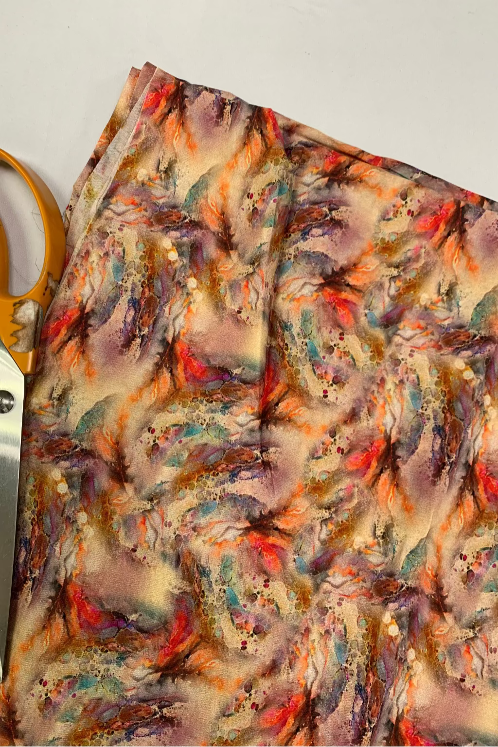 Colourful fabric with a floral pattern and a pair of scissors on a white background