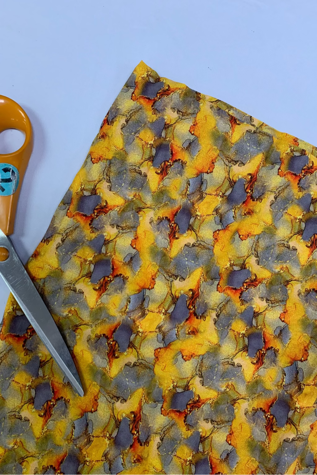 Colourful fabric with a pair of scissors on a light blue background