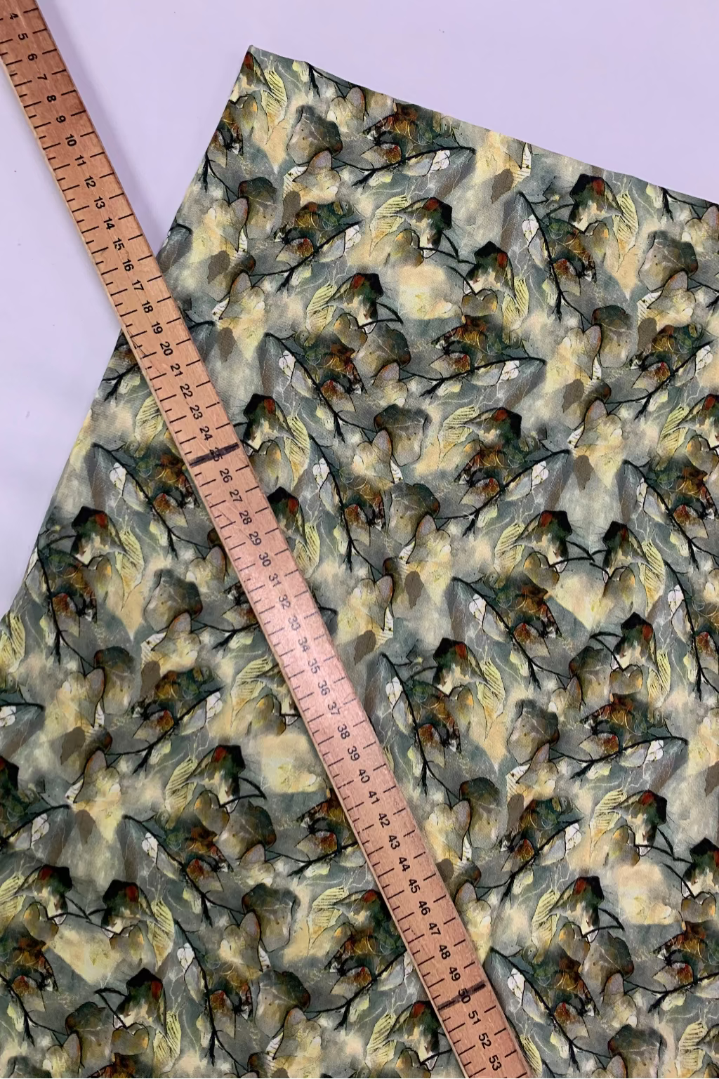 Fabric with leaf pattern and a ruler for scale on a light purple background