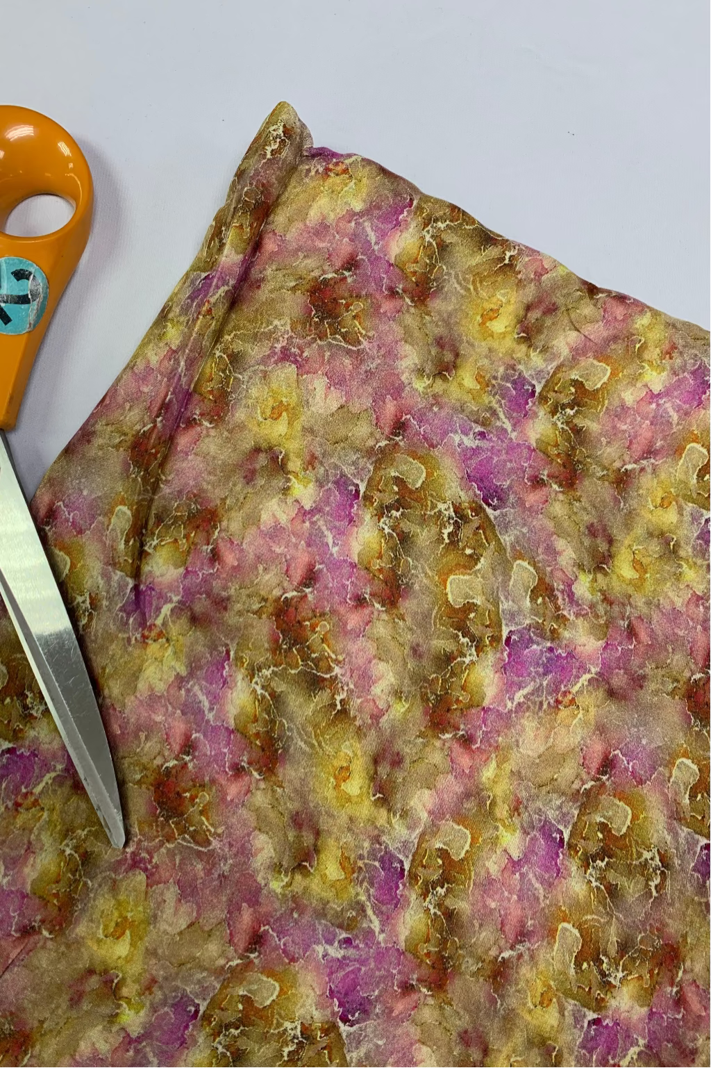 Colourful floral-patterned fabric with a pair of scissors on a white background
