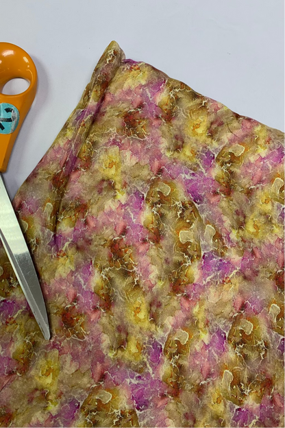 Colourful floral-patterned fabric with a pair of scissors on a white background