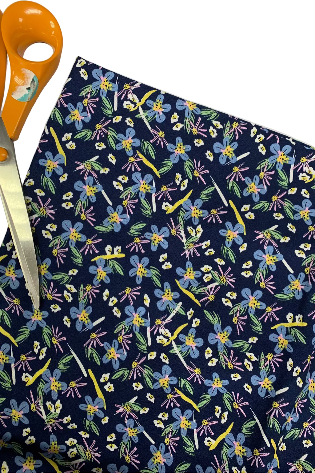 Floral-patterned fabric with colorful flowers on a navy background, accompanied by orange scissors.