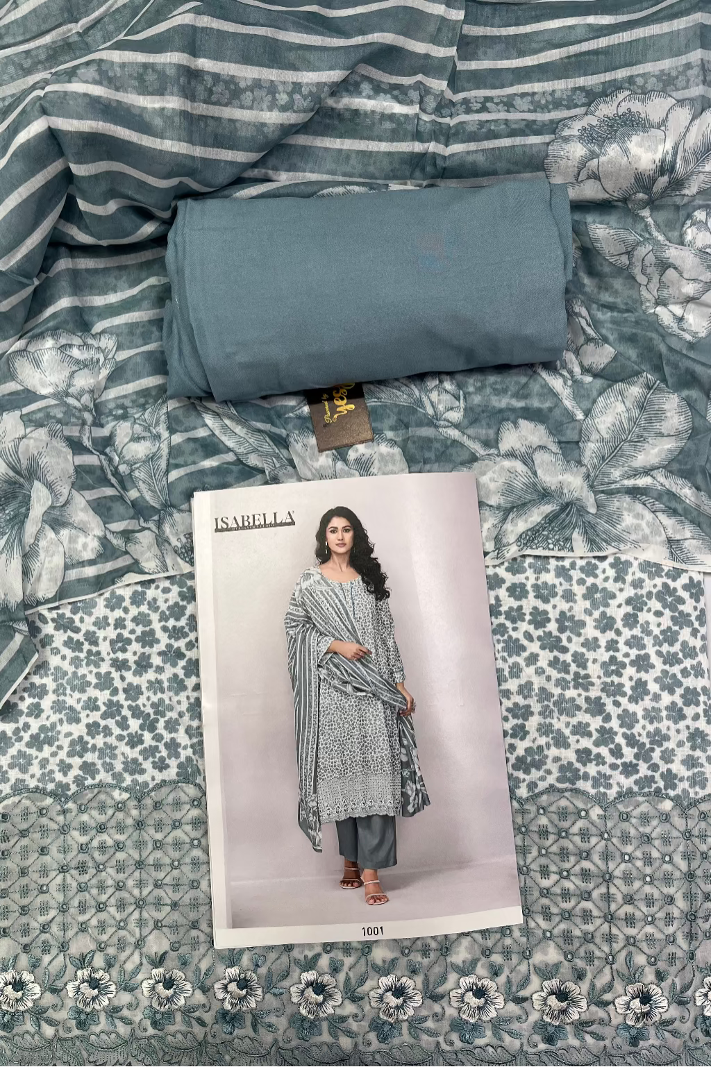 Roll of fabric with a floral pattern on a bed, featuring a product card with a model wearing a similar outfit.