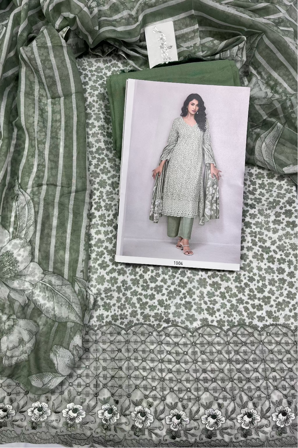 Fabric with floral and geometric patterns and a model wearing a green outfit on a patterned fabric background.